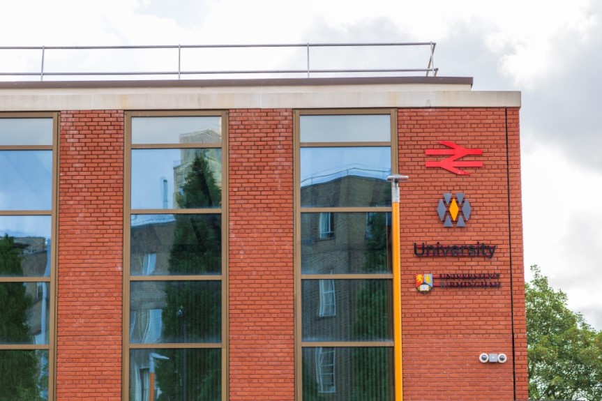 Side of University station building with Network Rail, Transport for West Midlands, University and University of Birmingham logos