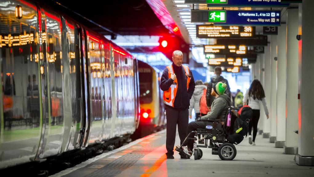 Wheelchair user being assisted by a member of staff on a railway station platform