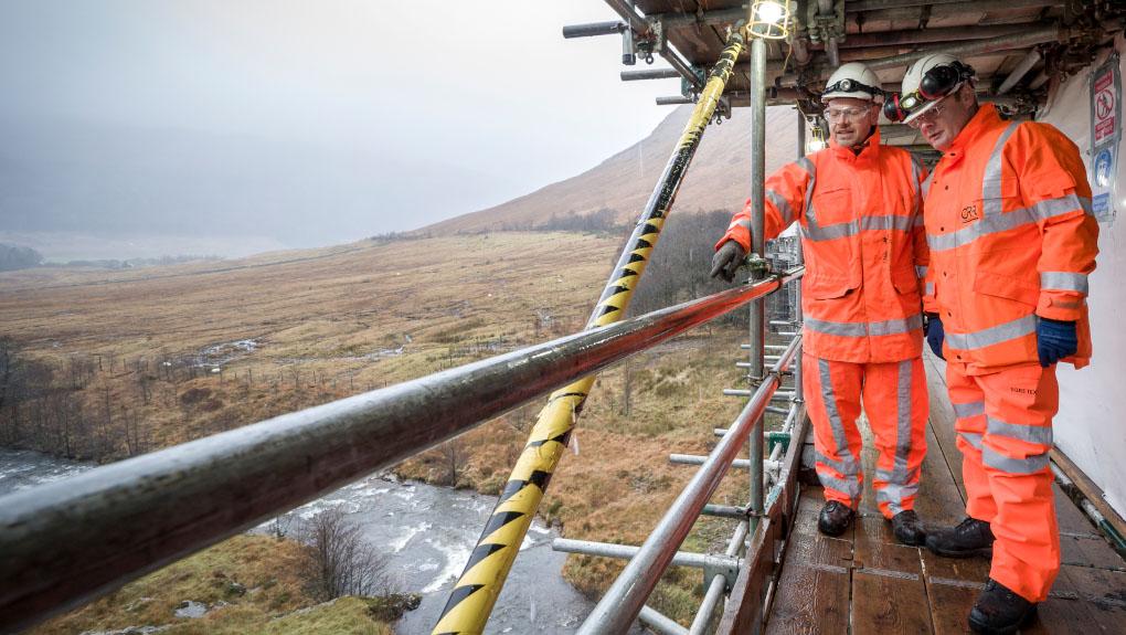 Two O R R inspectors in high visibility clothing and personal protective equipment on a health and safety visit in December 2019 to the Auch Viaduct (UB 310/151) and a nine span, steel railway viaduct near Tyndrum on the West Highland line