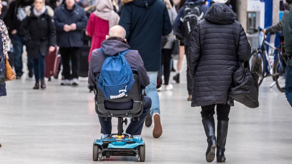 Mobility scooter user and other passengers at a railway station